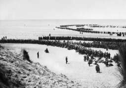 Britische Truppen warten auf ihre Evakuierung am französischen Strand<br>{Gemeinfreies Bild: „Dunkirk 26-29 May 1940. British troops line up on the beach at Dunkirk to await evacuation.“}